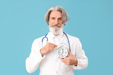 Doctor with alarm clock on color background