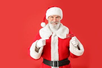 Fototapeta na wymiar Santa Claus with gift card on color background