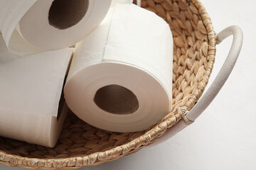 Wicker basket with rolls of toilet paper on white background, closeup
