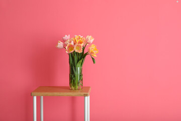 Bouquet of beautiful tulip flowers on table near color wall