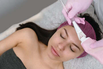 Obraz na płótnie Canvas Cosmetologist applaying peeling mask on female face in beauty salon