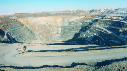 Massive open-pit mine with a truck riding around it
