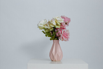Pink vase with flowers on the table on a white background. Place for an inscription. Close-up.