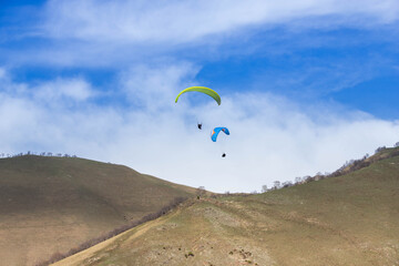 Fototapeta na wymiar paragliders fly among the mountains