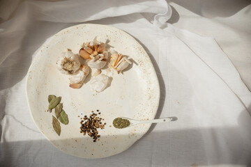 Cooking seasoning set: garlic, bay leaf, pepper and herbs on a handmade ceramic plate. . High quality photo