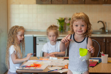 three children are engaged in creative work at the table at home: draw, cut the applique
