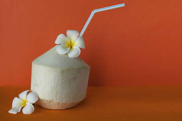 Coconut for drink with Plumeria flowers on the orange background 