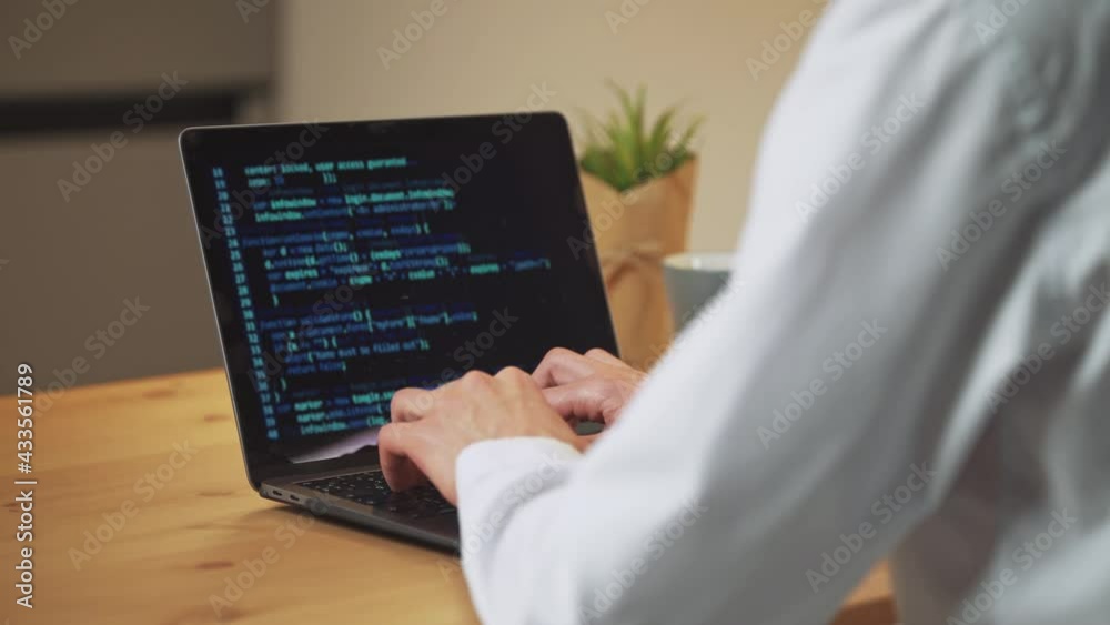 Wall mural male programmer is working on creating software, typing program code on a laptop keyboard, programme
