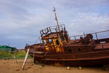 Fototapeta premium Ship graveyard. A sunken rusty abandoned fishing vessel in Russia, the Kola Peninsula, the Barents Sea, Teriberka.