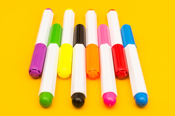Multicolored markers on a yellow background. Photo for drawing with felt-tip pens.