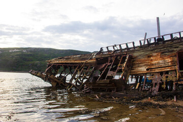 Ship graveyard. A sunken rusty abandoned fishing vessel in Russia, the Kola Peninsula, the Barents Sea, Teriberka.