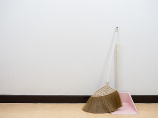 Broom and dustpan on the floor at white wall copy space interior the house