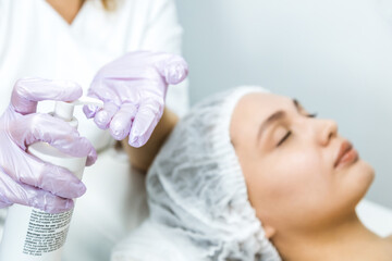 Facial skin care and protection. A young woman at a beauticians appointment. The specialist cleans the skin before applying the mask cream