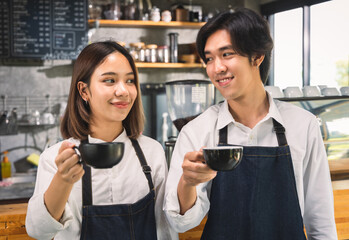 Two asian coffee waitress making cup of hot coffee latte in coffee shop cafe. Barista working with coffee machine in shop.