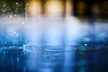 small splashing crown from rain's droplet when fall down on the floor in rainy day with blue shade color tone and golden sun light behind