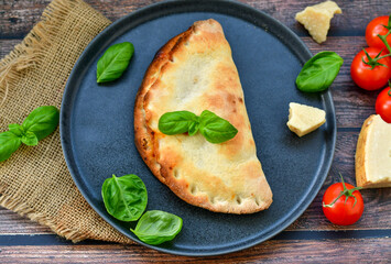 Home made italian calzone vegetarian  pizza with  tomatoes, mozzarella and parmesan cheese and fresh basil 