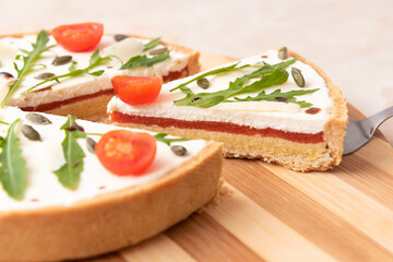 Tart with feta cheese, tomato and rhubarb on wooden plate