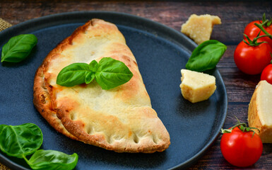 Home made italian calzone vegetarian  pizza with  tomatoes, mozzarella and parmesan cheese and fresh basil 
