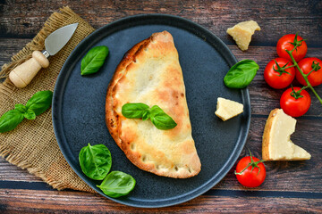 Home made italian calzone vegetarian  pizza with  tomatoes, mozzarella and parmesan cheese and fresh basil 