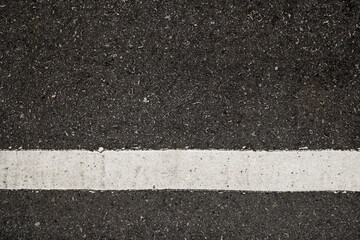 Fototapeta premium Surface grunge rough of asphalt, Seamless tarmac dark grey with white line on the road and small rock, Texture Background, Top view