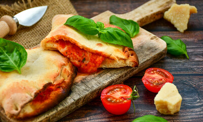 Home made italian calzone vegetarian  pizza with  tomatoes, mozzarella and parmesan cheese and fresh basil 