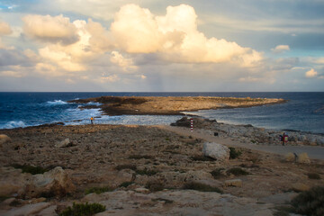 Fototapeta na wymiar Light shining on small island in the ocean at a beach in Qawra, Malta at sunset.