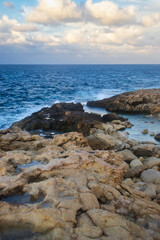 Fototapeta na wymiar Rocks with pools of water leading out into the blue ocean on a fall evening in Qawra, Malta