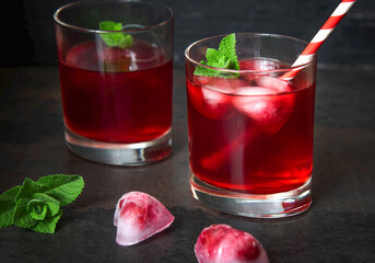 Cranberry juice with heart shaped ice cubes on a dark background. Top view