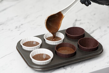 The chocolate cake dough is poured into a mold with beautiful paper cups.Close-up
