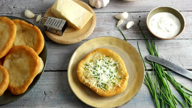 Traditional Hungarian Langos with garlic, cheese and sour cream,  4K UHD dolly side pan 