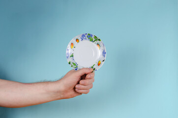 Man holding White saucer with painted flowers.