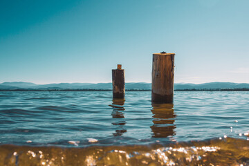 two wooden piles washed by the waters of the lake with the mountains in the background