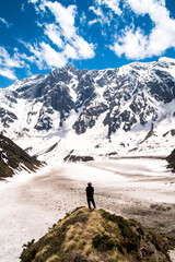 A lone hiker looks at the view of the Himalayas on the Beas Kund trek in northern India
