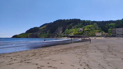 Beach in the bay, green mountain slopes, footprints in the sand.
