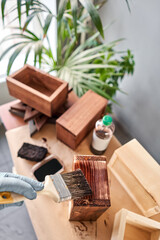 Man carpenter varnishing wooden crate for flowers with brush in her small business woodwork workshop. In your work, do you use stains or wood preservatives to show the wood pattern.