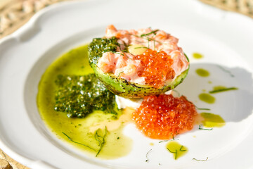 Raw salmon tartare. Fresh salmon, avocado and pesto sauce with red caviar on a plate. Selective focus