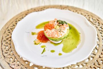 Raw salmon tartare. Fresh salmon, avocado and pesto sauce with red caviar on a plate. Selective focus