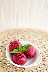 Italian gelateria. Berry ice cream with mint leaf. three balls in a white bowl on a vintage table. sorbet