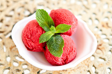 Italian gelateria. Berry ice cream with mint leaf. three balls in a white bowl on a vintage table. sorbet