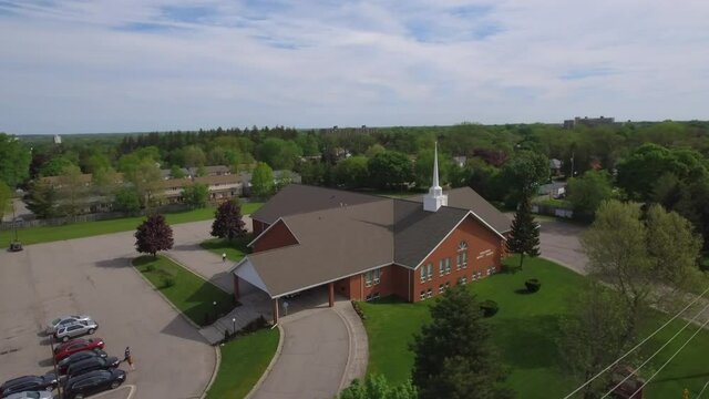 Aerial shot of church building and parking lot with members arriving to church