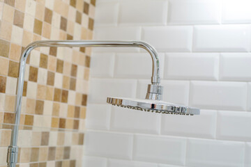 Stationary shower head on the background of ceramic tiles. Detail of a bathroom with chrome elements. Close-up © Dmitry