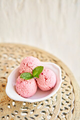 Strawberry ice cream with mint leaf. three balls in a white bowl on a vintage table. sorbet