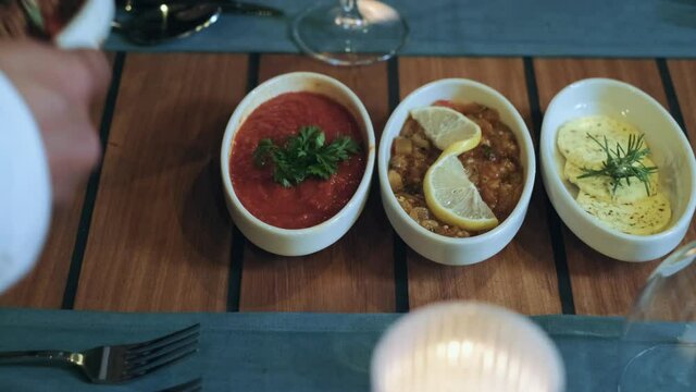 the waiter puts the starters to the table.
in the restaurant the waiter is putting the appetizers on the table. 4K.