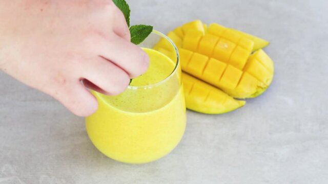 Decorating smoothie with mint leaf,tropical mango smoothie or mango lassi in a glass
