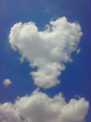 Naklejka na ściany i meble Heart shaped cloud on blue sky close up.