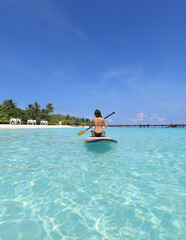 sports girl with paddle on surfboard in the Ocean, Maldives
