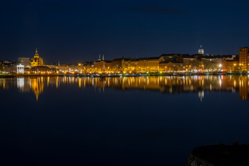 Fototapeta premium A beautiful panorama of downtown Helsinki waterfront with illuminated buildings casting reflections on the calm sea.