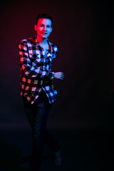 A guy in a plaid shirt with red and blue lighting in the studio on a black background