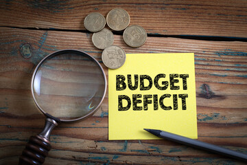 Budget Deficit. Euro cash and magnifying glass on a wooden background