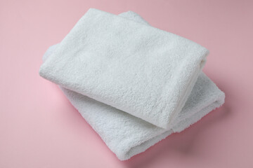 Clean folded towels on pink background, close up